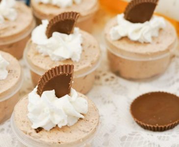 Skrewball pudding shots with whipped cream and chocolate garnish on a table.
