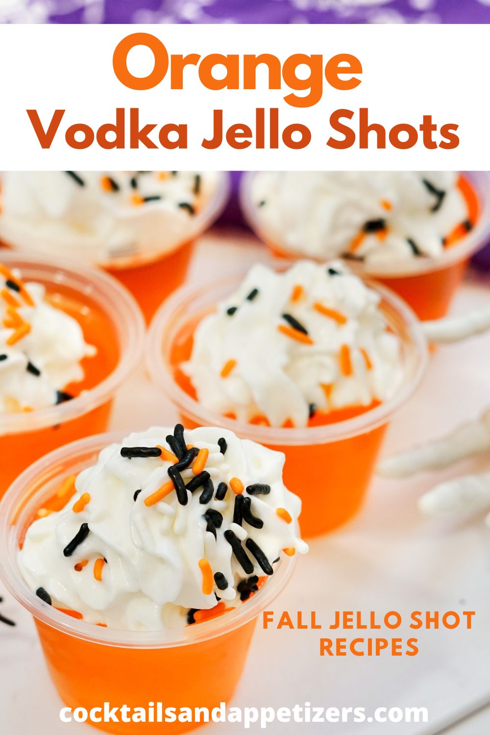 Orange Vodka Jello shots with whipped cream and sprinkles sit in condiment cups on a tray.