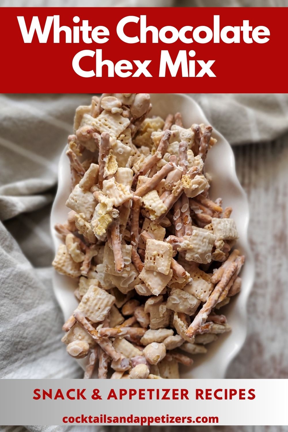 White Chocolate Chex Mix in a white serving bowl with a cloth alongside.