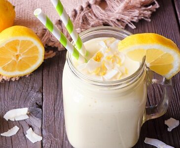 Bourbon Lemonade Ice Cream Float in a mason jar with lemon slice and straws. Sits on a wooden table ready to serve.