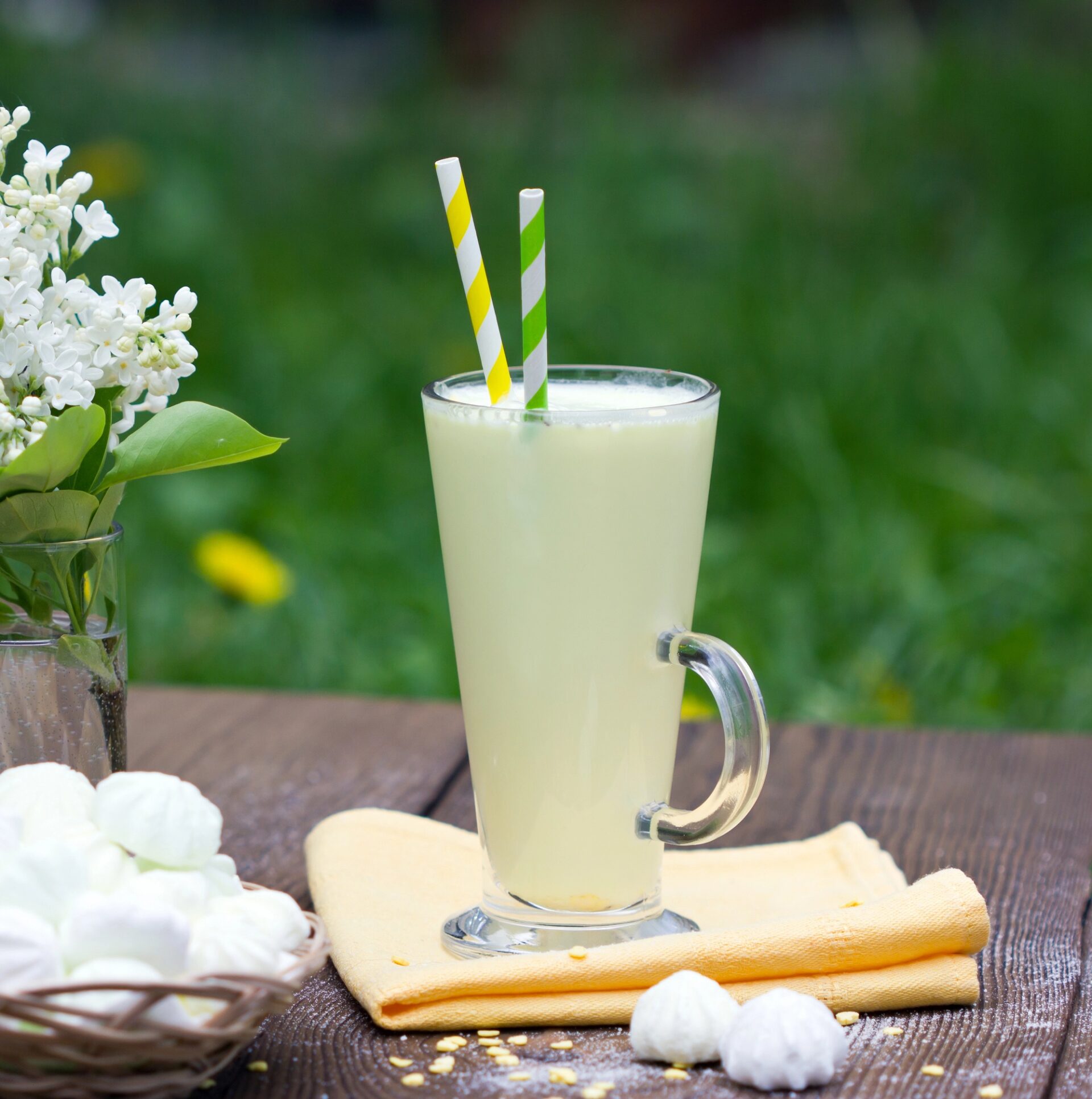 A large glass of bourbon lemonade float on an outdoor picnic table.