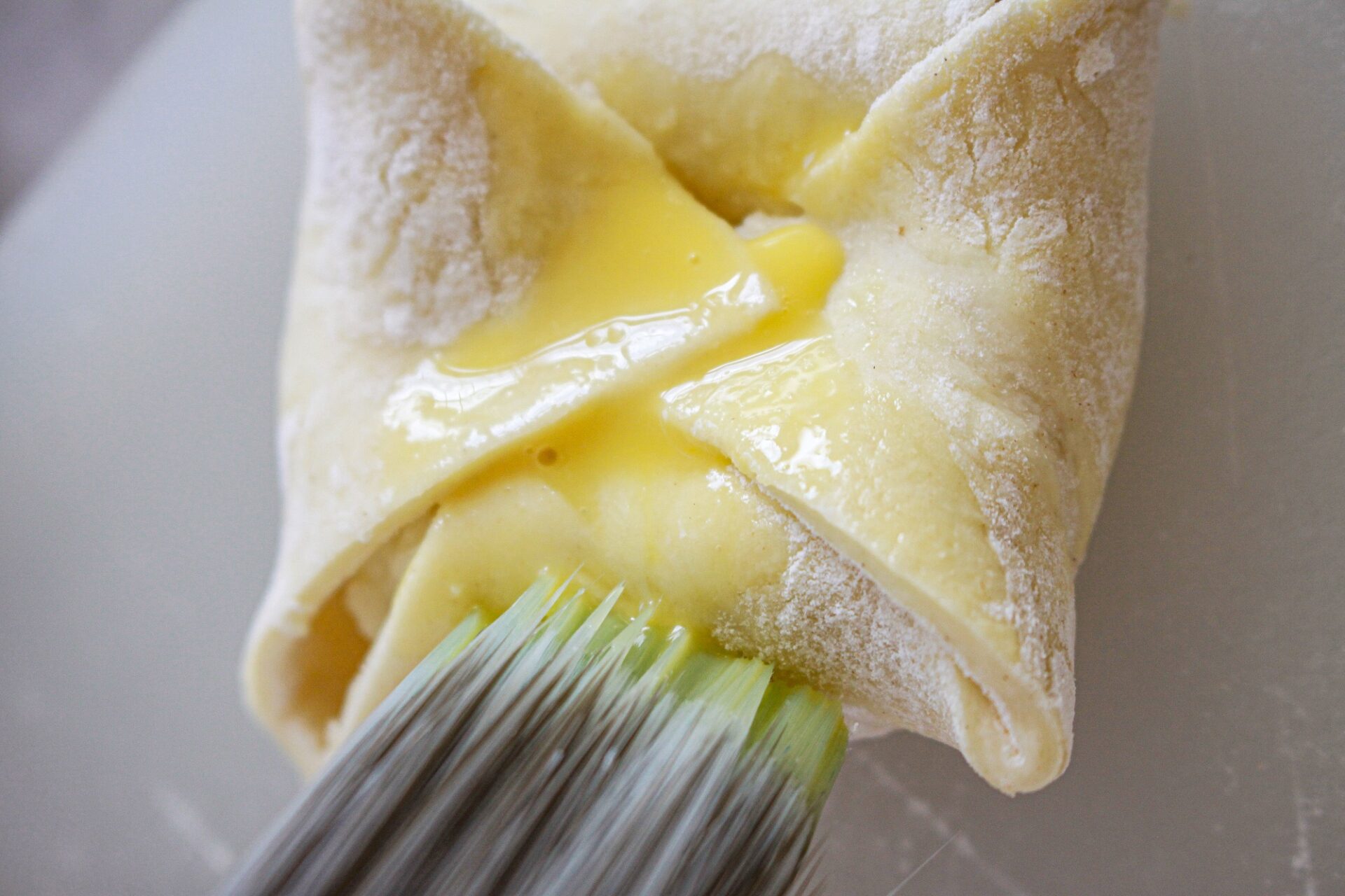 Brushing egg wash onto fully folded potato bite pastry.