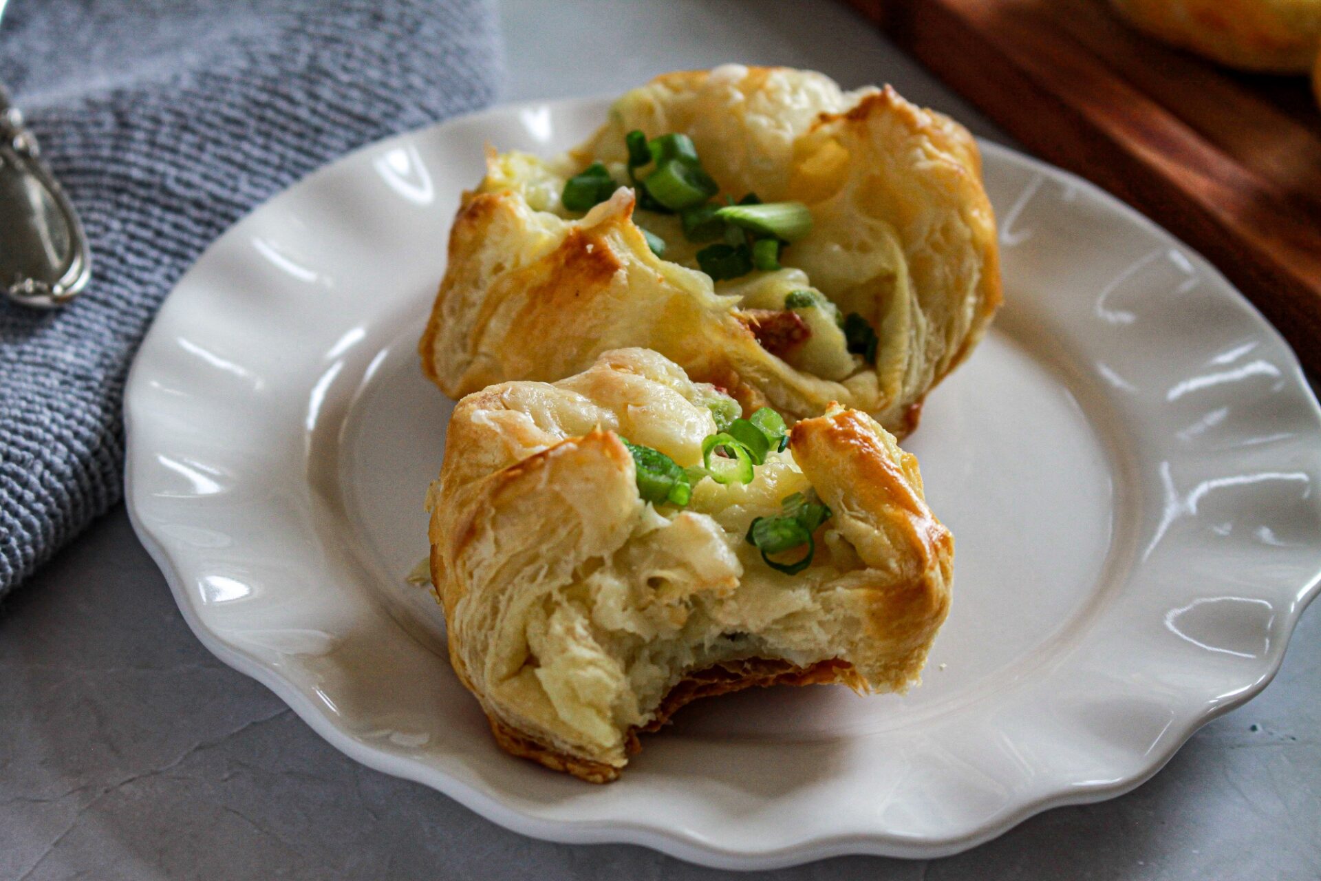 Two baked potato bites on a plate. One has a bite taken out of it.