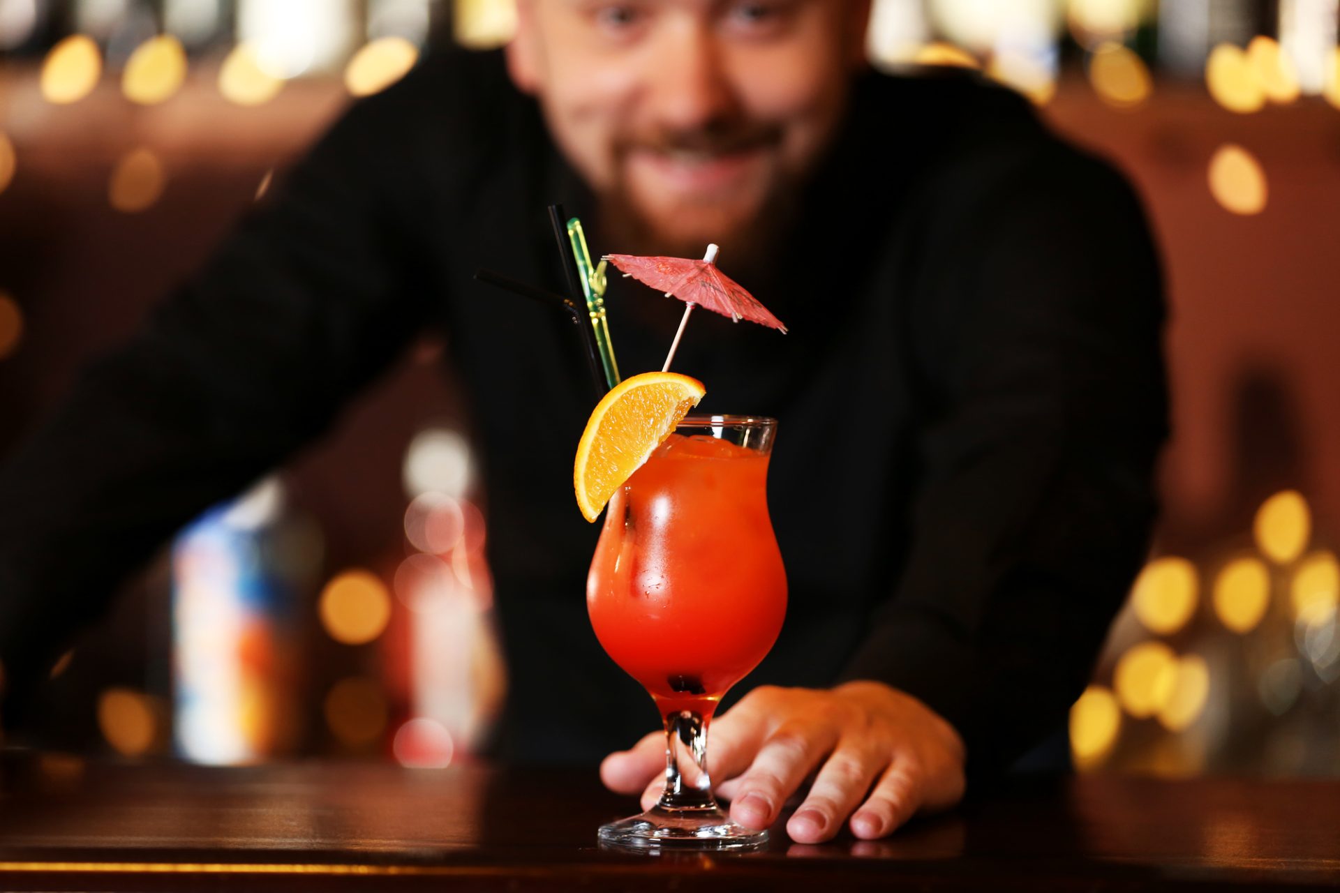 Home bartender pushing a tropical pink cocktail across the bar to you.