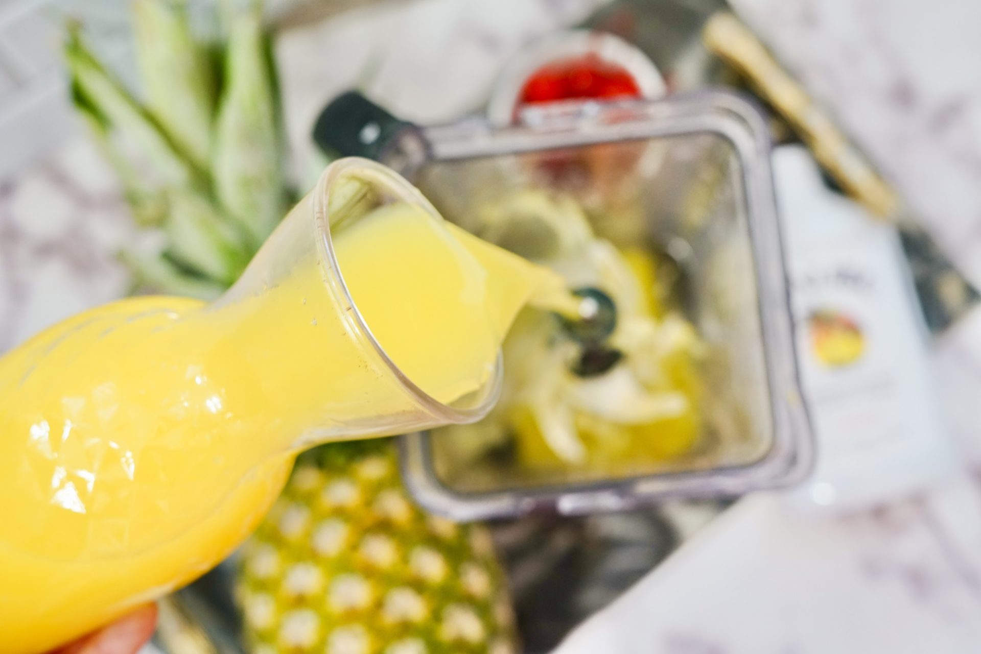 Pouring pineapple juice to a blender of ice.