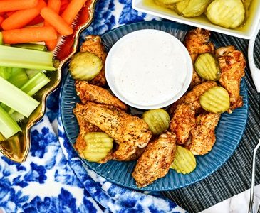 Air Fryer appetizer collection including these spicy chicken wings surrounded by fresh vegetable slices and a dipping sauce.