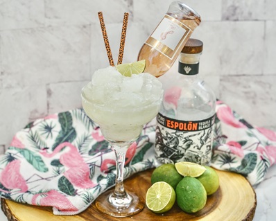Rosé Margarita in a glass with straws and a lime wedge garnish.
