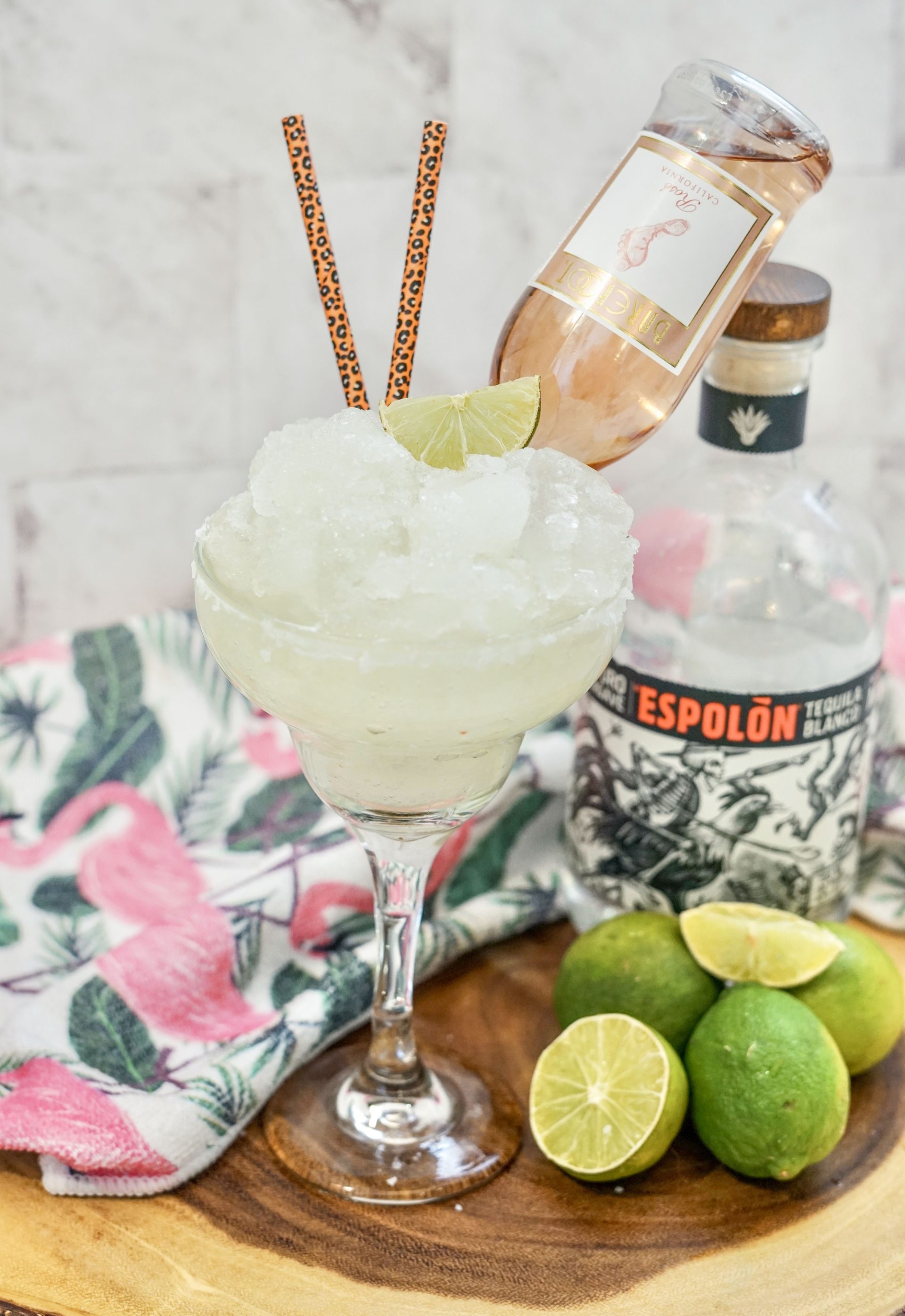 Rosé Margarita in a glass with straws and a lime wedge garnish.