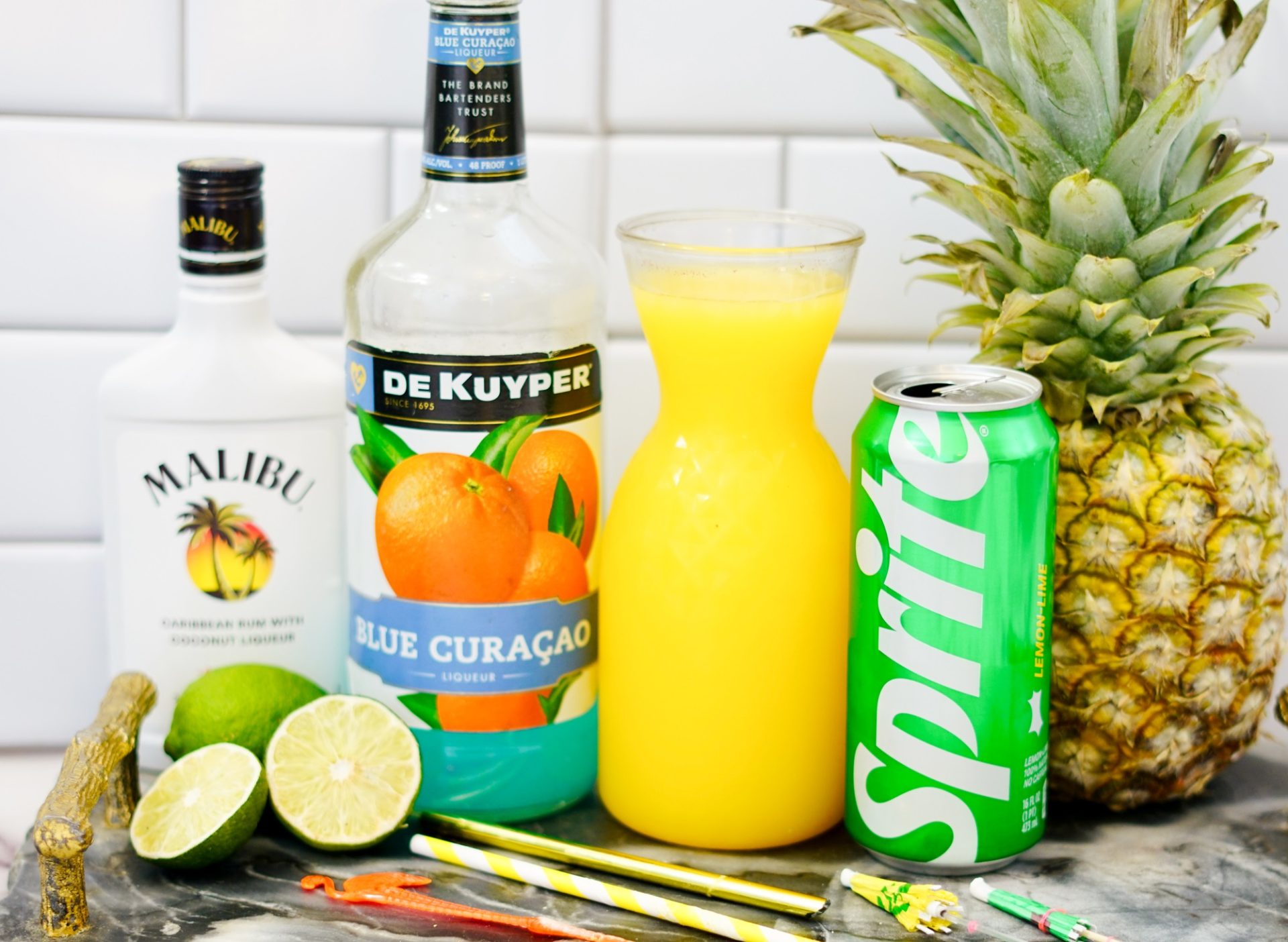 Malibu rum, blue curacao, Sprite and pineapple juice on a counter.