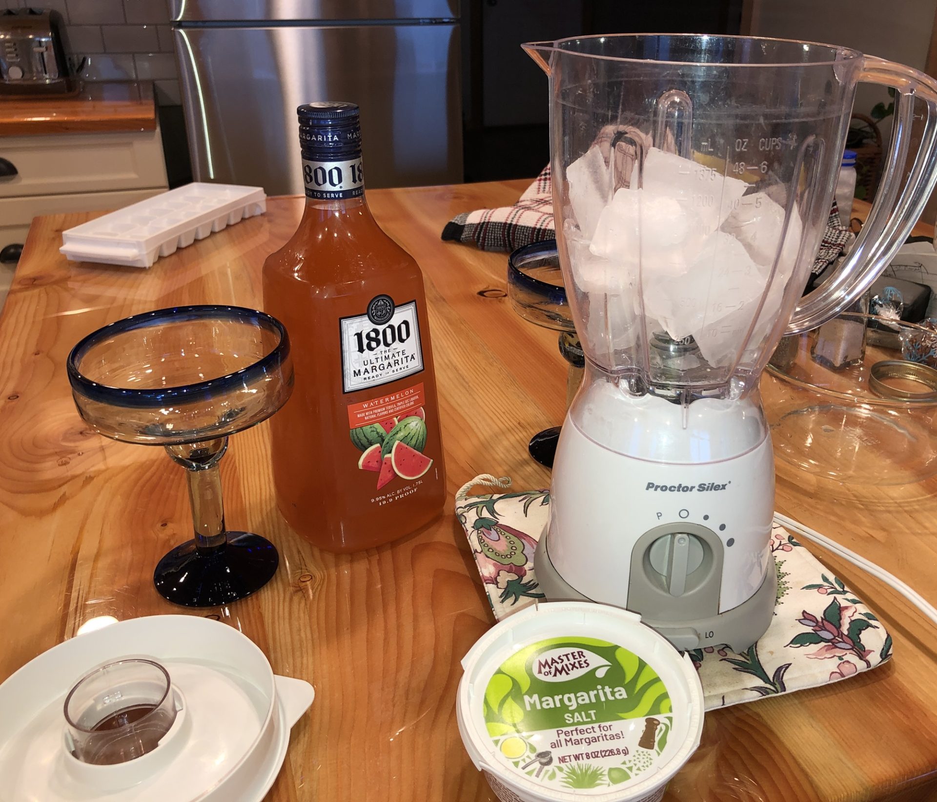 Blender filled with ice with 1800 tequila bottle behind it along with salt.