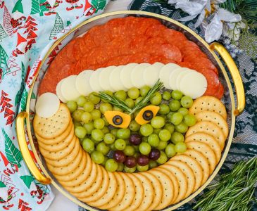 Grinch Charcuterie board sits on a Christmas decorated table.