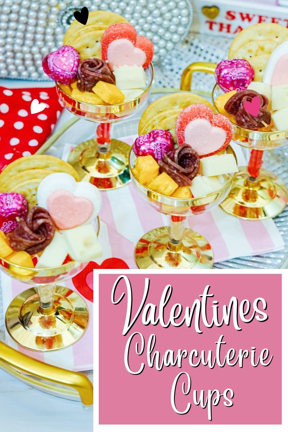 Charcuterie cups decorated for Valentines day sit on a food table.