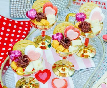 Charcuterie cups for Valentines on a tray, filled with crackers, cheese, and candy.