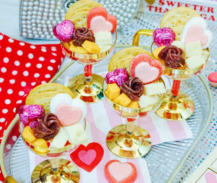 Charcuterie cups for Valentines on a tray, filled with crackers, cheese, and candy.