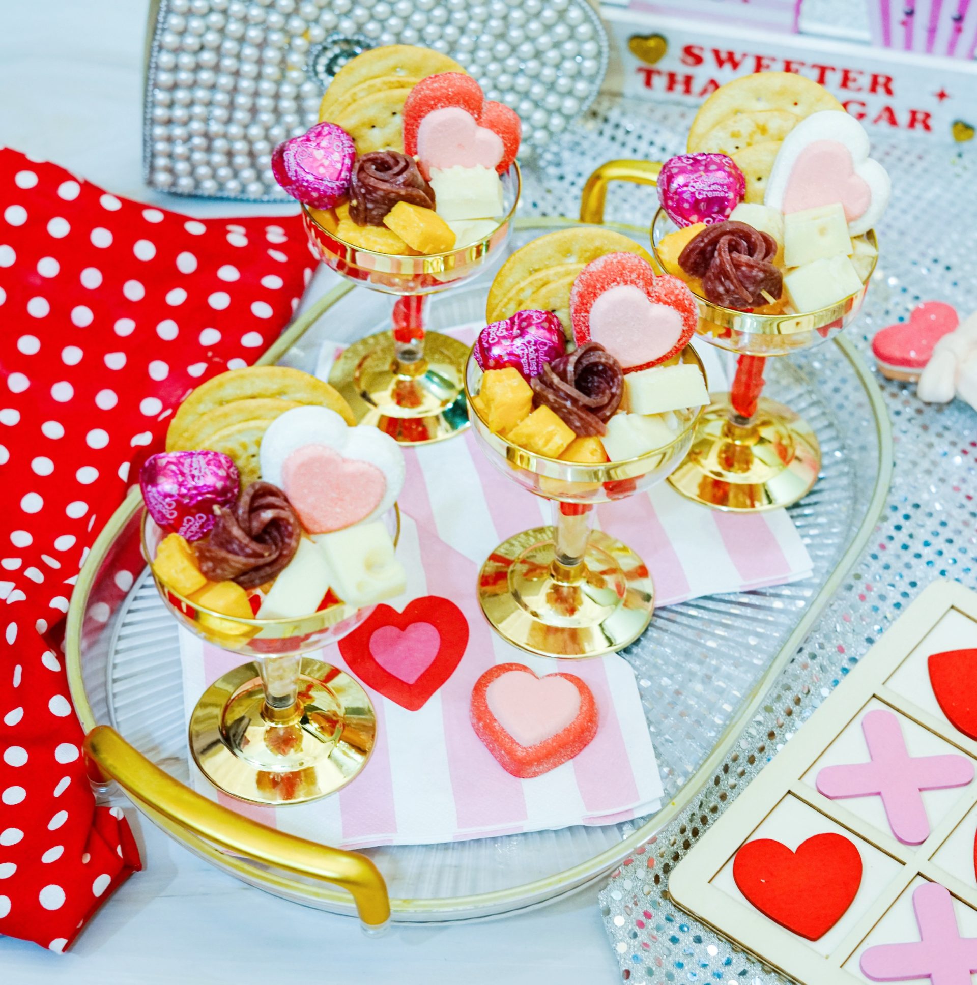 Charcuterie cups filled with cheese, meat, crackers and Valentines candy sit on a tray.
