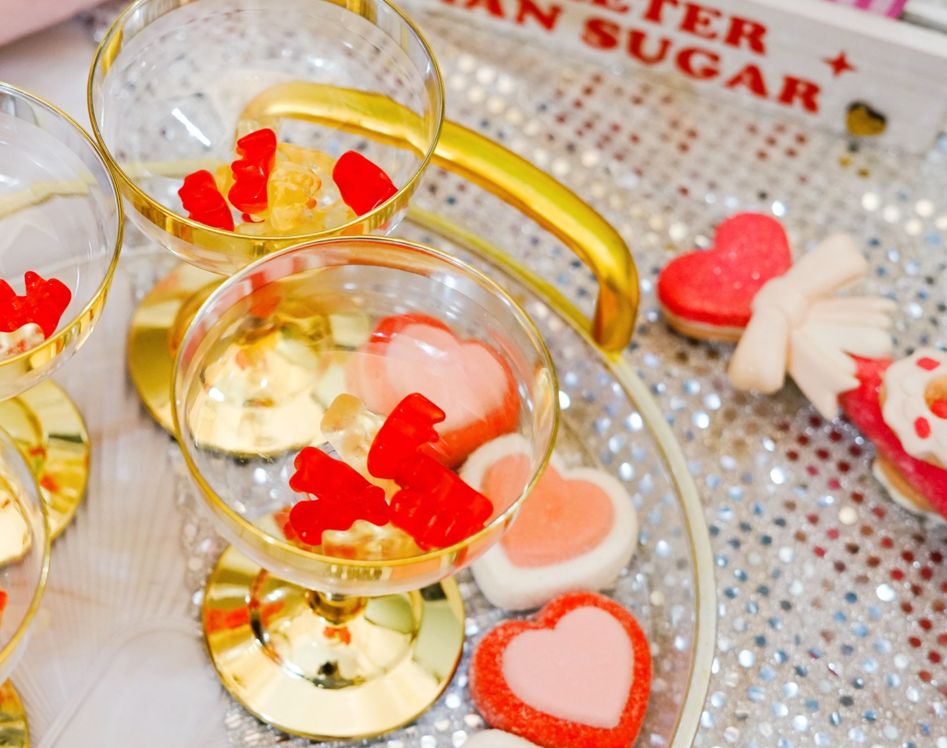 Coupe glasses with red and gold gummy bears on a tray.