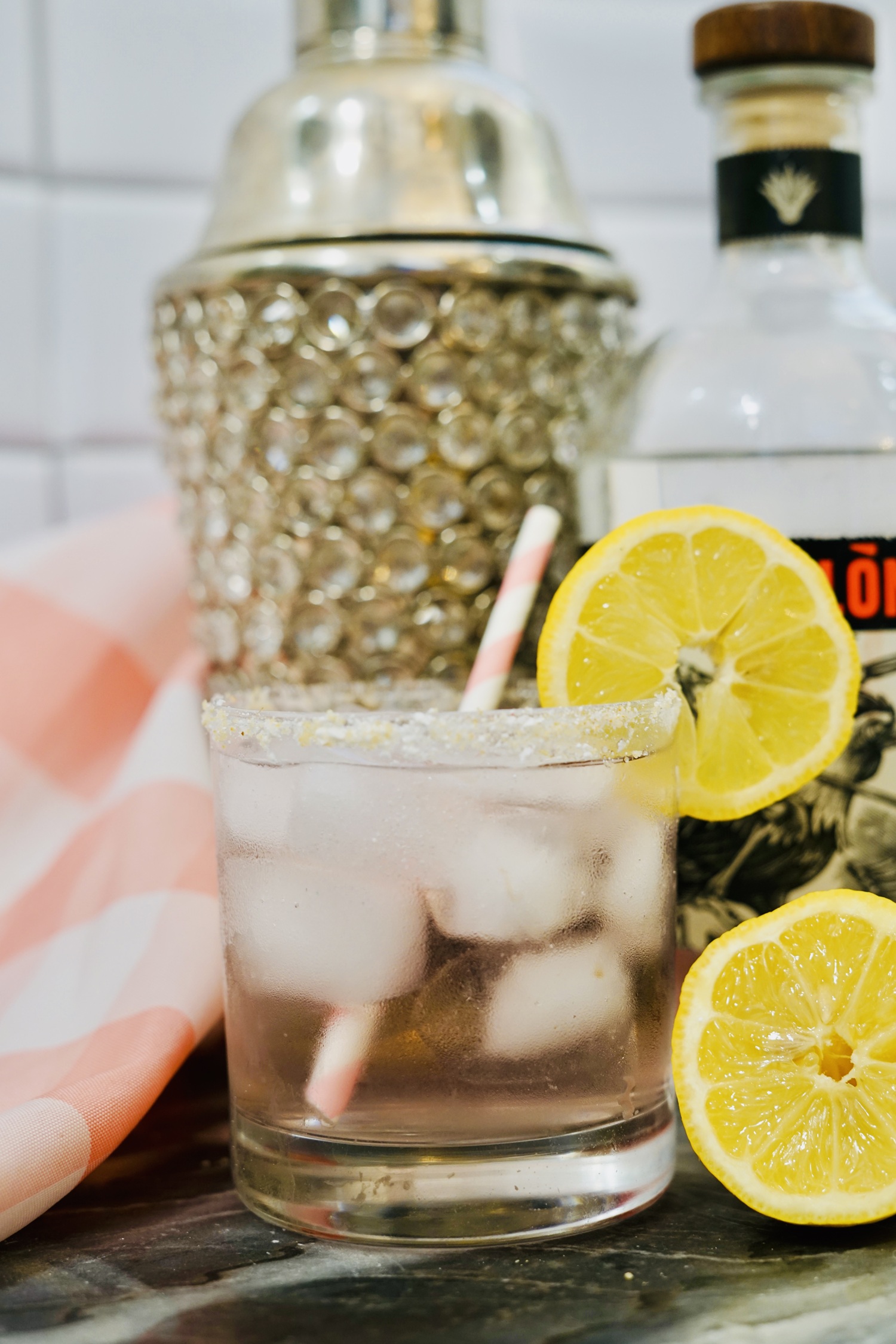 Pink Tequila Lemonade over ice in a salt rimmed glass sits on a Galentines day cocktail table.