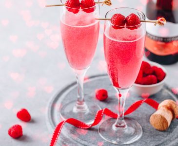 2 Galentine's cocktails in champagne glasses on a silver tray.