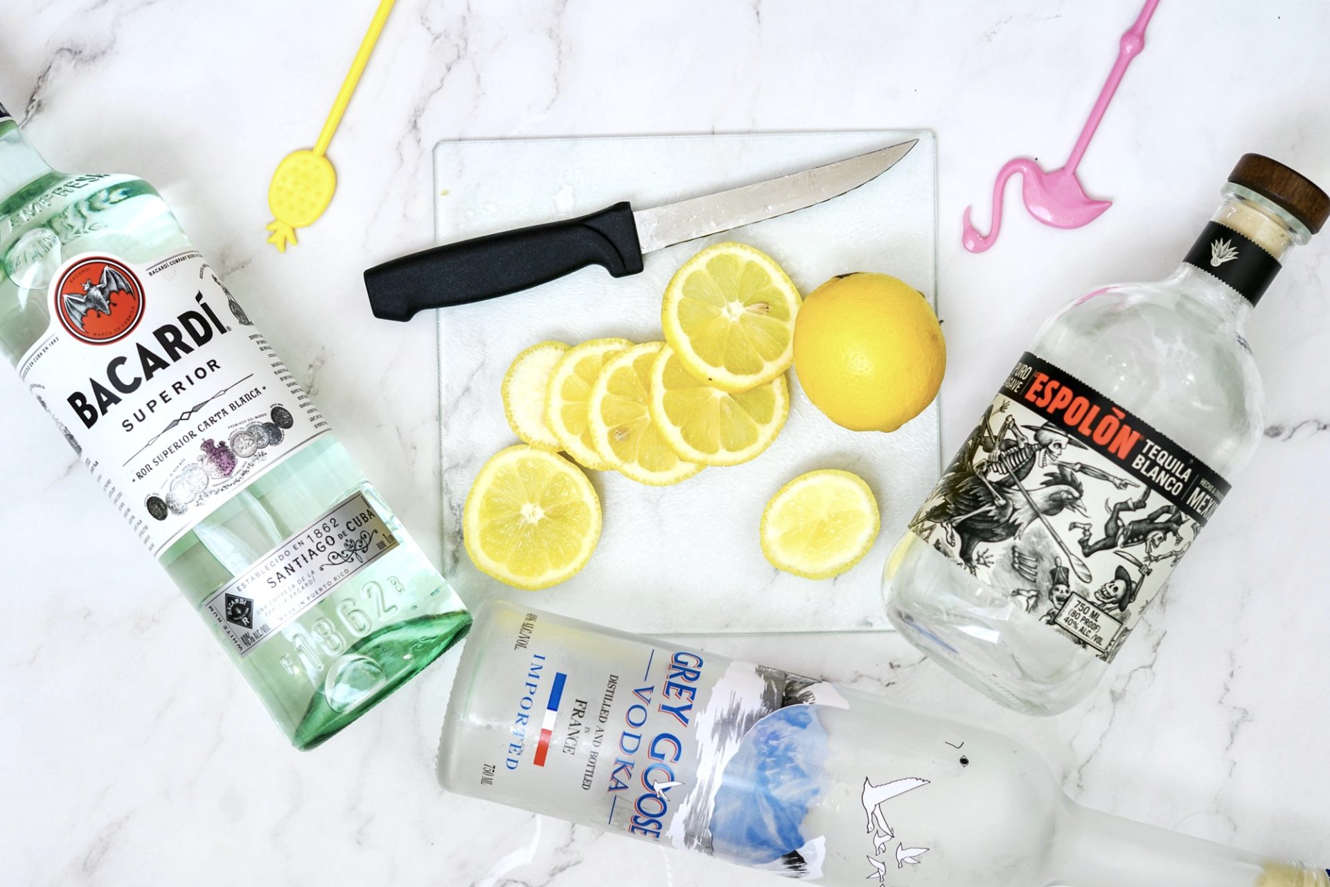 Bottles of rum, tequila and vodka on a cutting board with slices of lemon