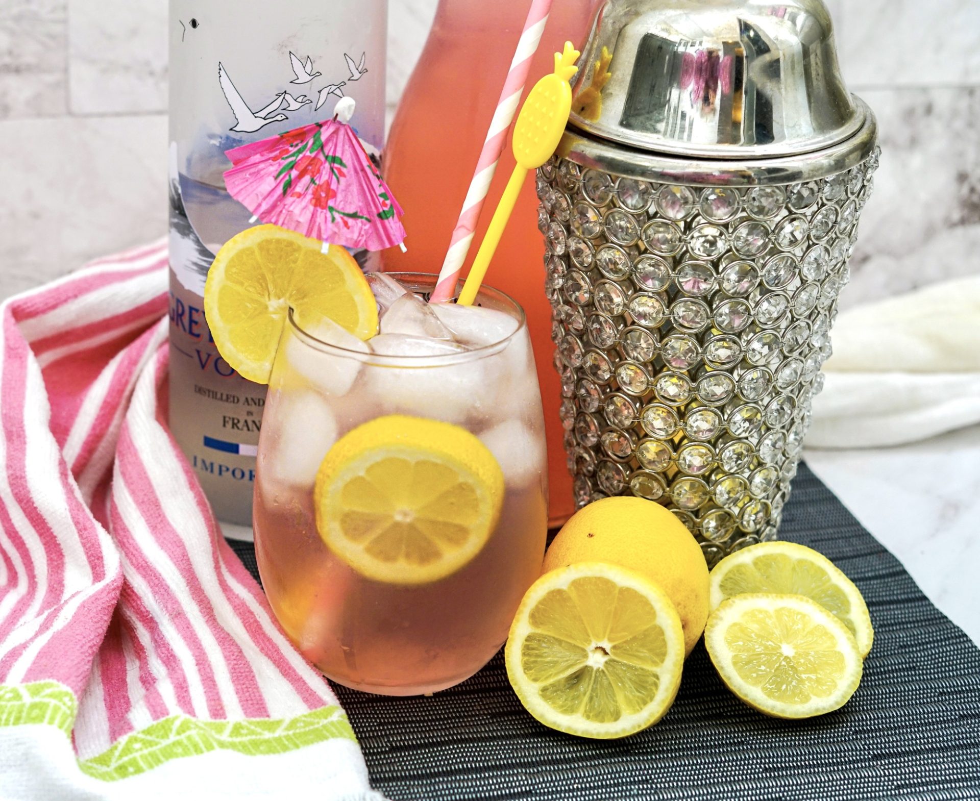 Pink Long Island in a highball glass with ice and fresh lemon slice garnish.