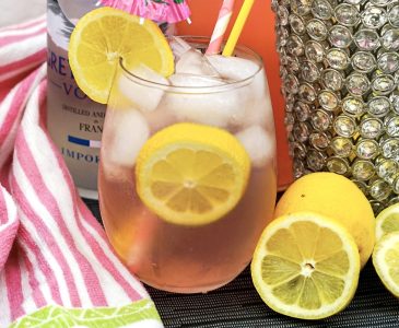 Pink Long Island cocktail in highball glass with ice and lemon slice garnish.