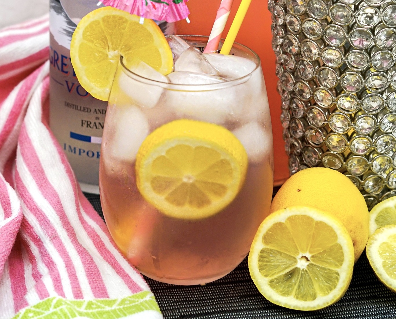 Pink Long Island cocktail in highball glass with ice and lemon slice garnish.