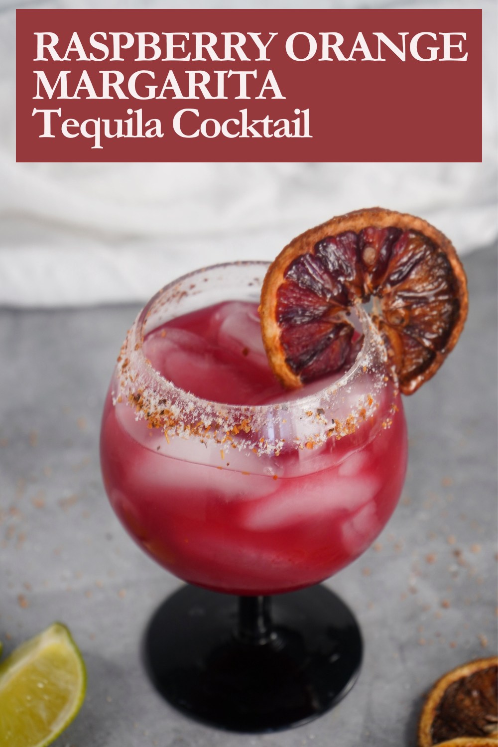 Raspberry orange margarita in a wine glass with a Tajin rim and lots of ice.